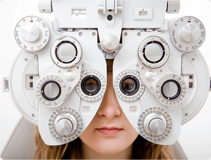 A woman is looking through the lens of an eye test.