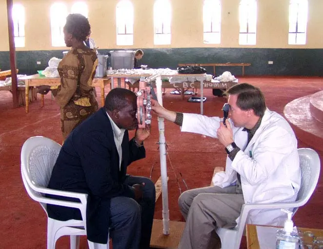 Dr. Rousselo volunteering in kenya doing eye check for a man