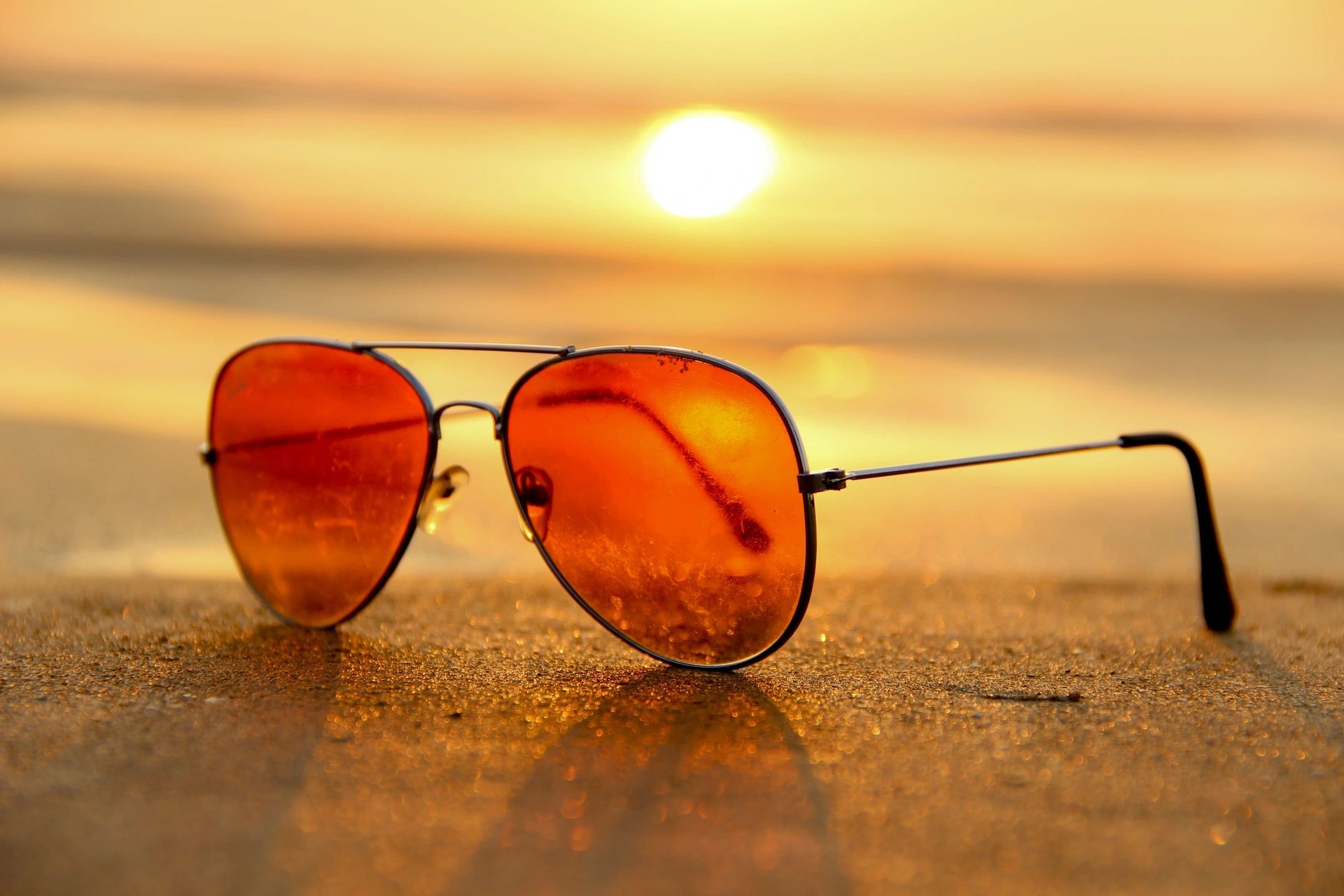 A pair of sunglasses sitting on top of the sand.